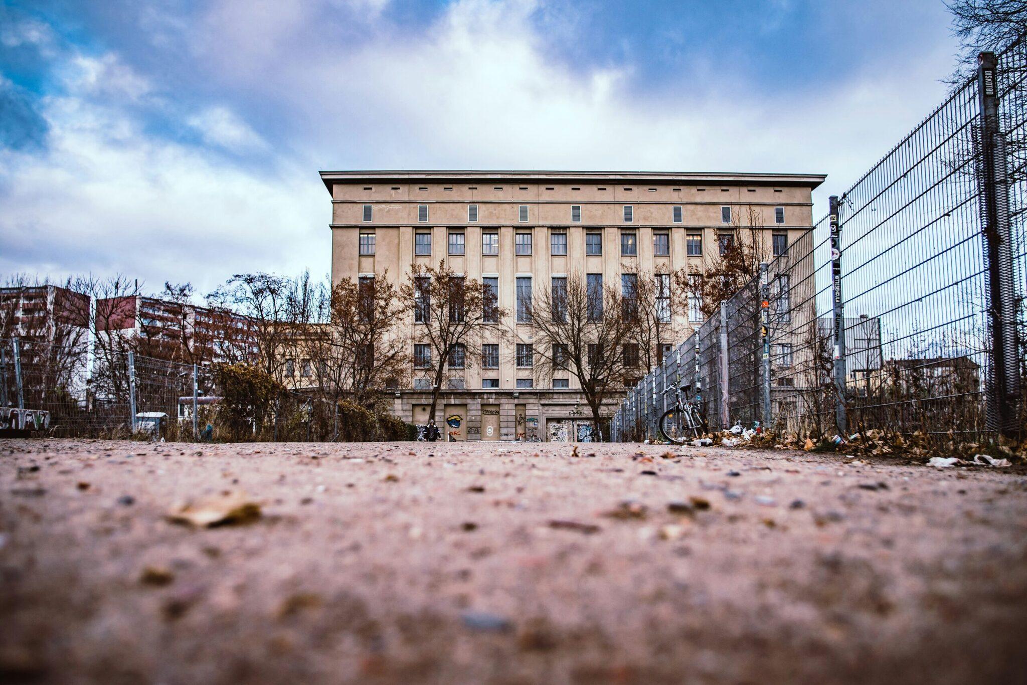An empty urban playground bordered by historic brick buildings and metal wire fencing