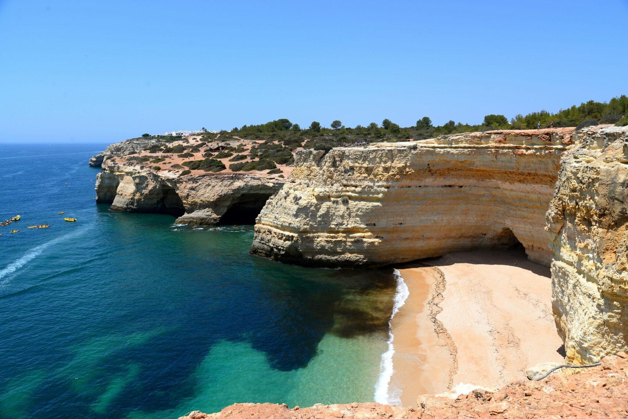 Ein kleiner Goldstrand, eingerahmt von Kalksteinklippen und kristallklarem türkisem Meer unter blauem Himmel