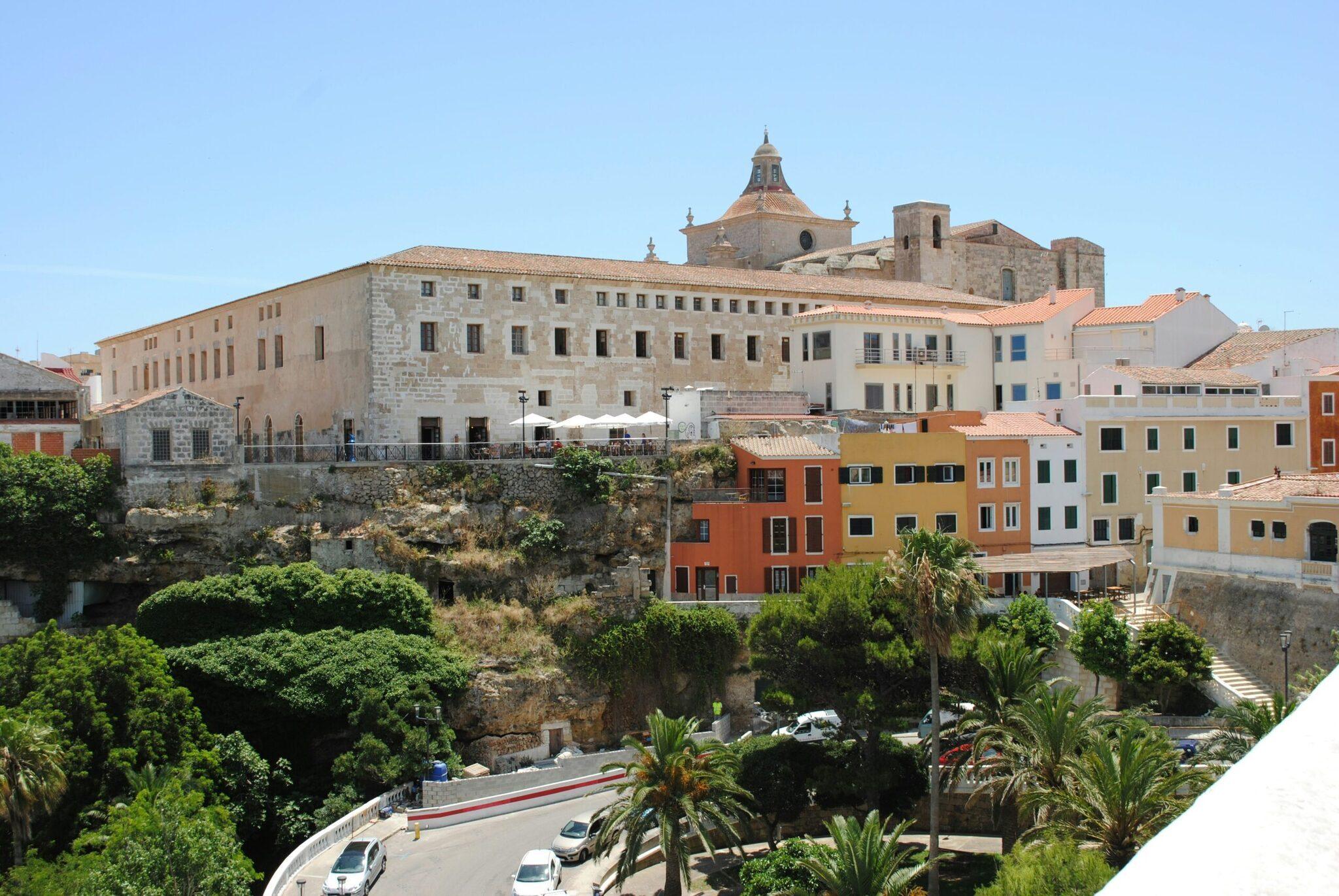 Vista de una ciudad costera mediterránea con iglesia barroca, edificios de colores y arquitectura histórica sobre acantilado