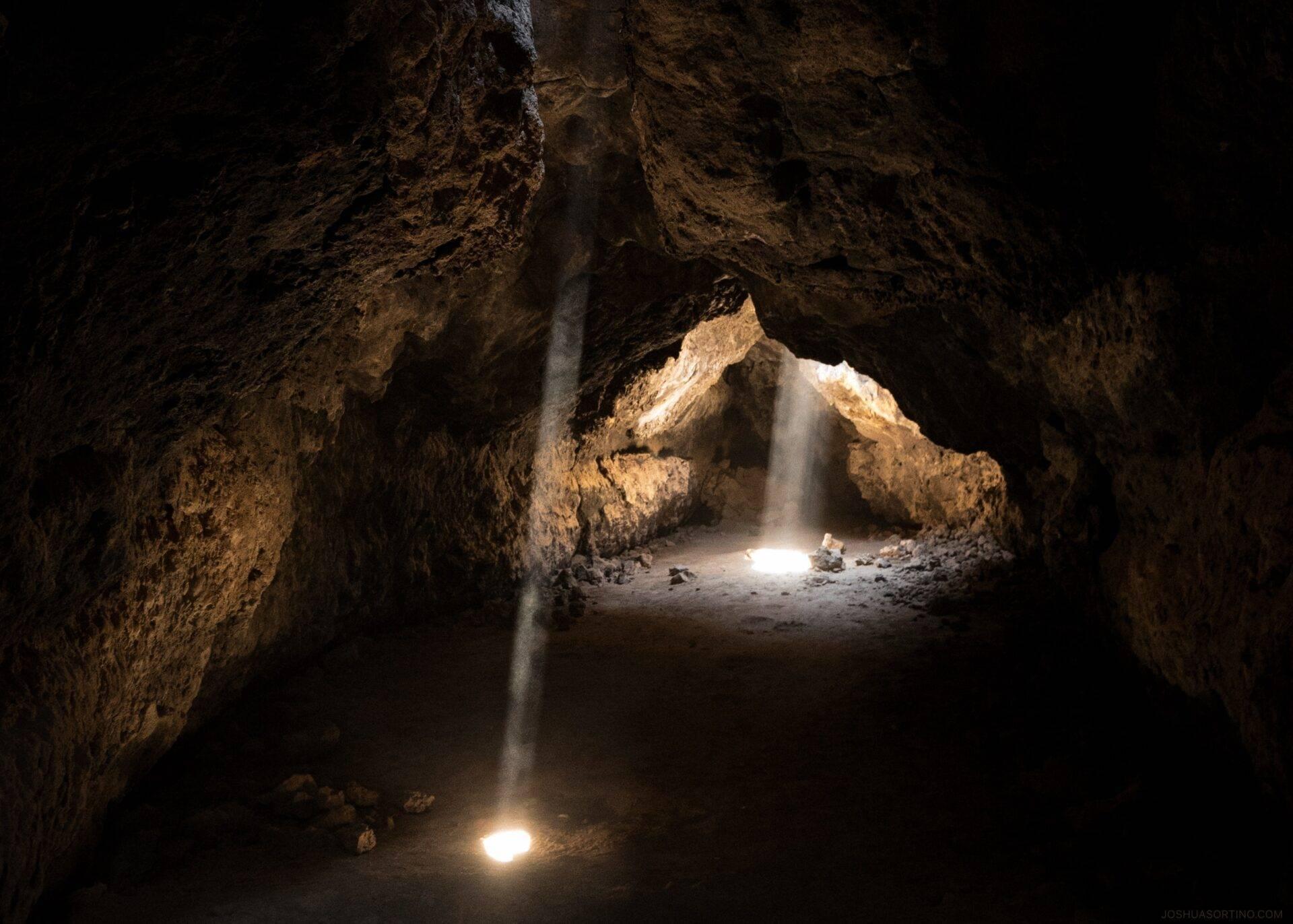 Inneres einer Kalkhöhle mit Lichtstrahlen, die die Dunkelheit durchdringen, und felsigem Boden