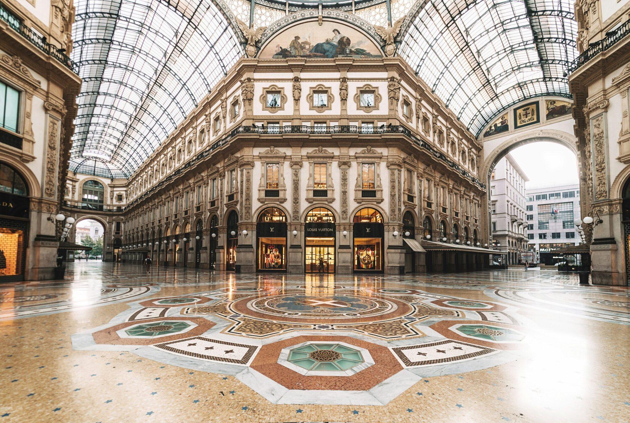Galerie marchande historique avec verrière, dallage ornemental et façades néoclassiques, apparemment déserte