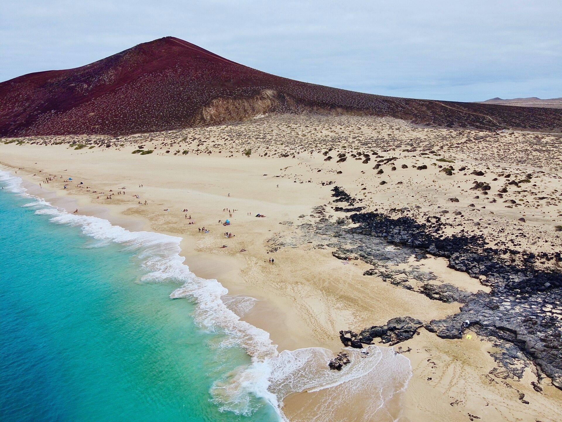 Côte volcanique des îles Canaries sous un ciel bleu, voyageur en balade