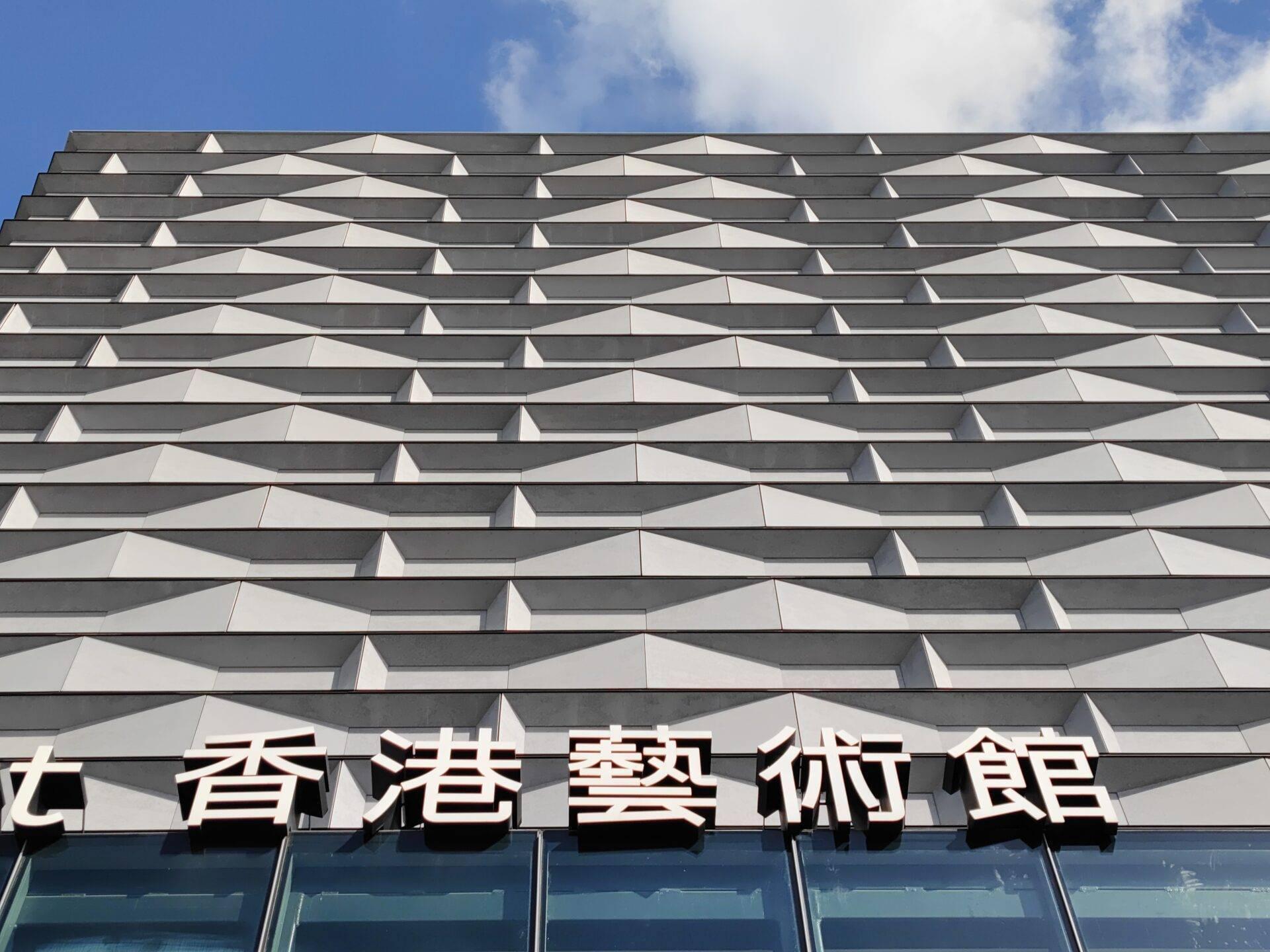 Façade architecturale moderne d’un musée à Hong-Kong avec panneaux de signalisation en caractères chinois et design géométrique ondulé