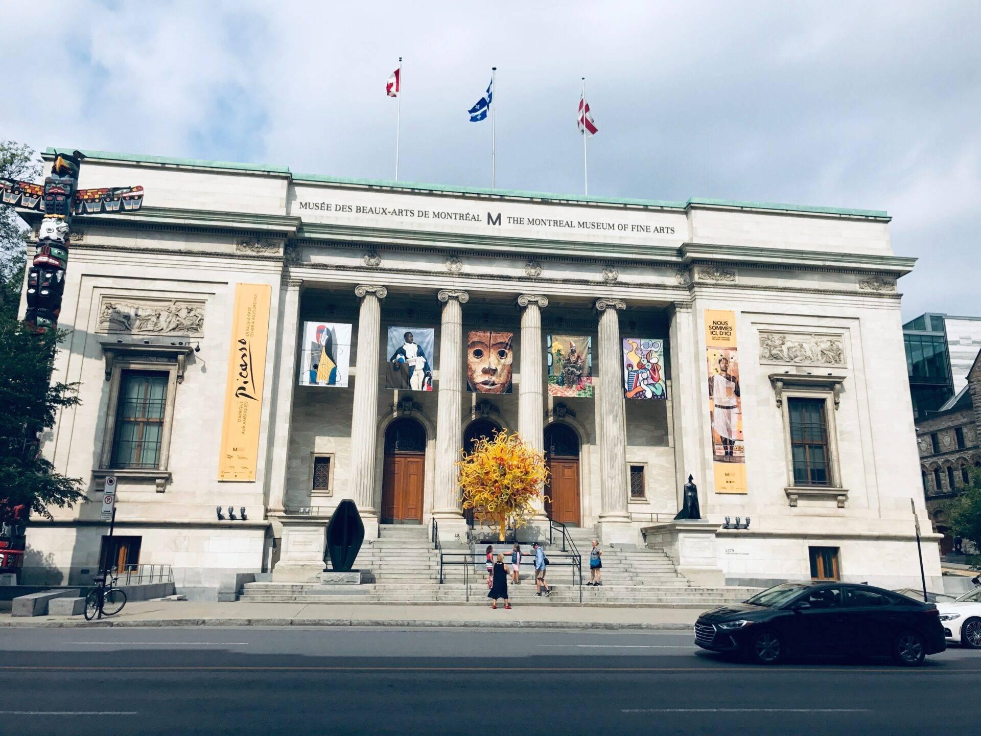Façade classique d’un musée des beaux-arts avec colonnes blanches, drapeaux et banderoles jaunes d’exposition