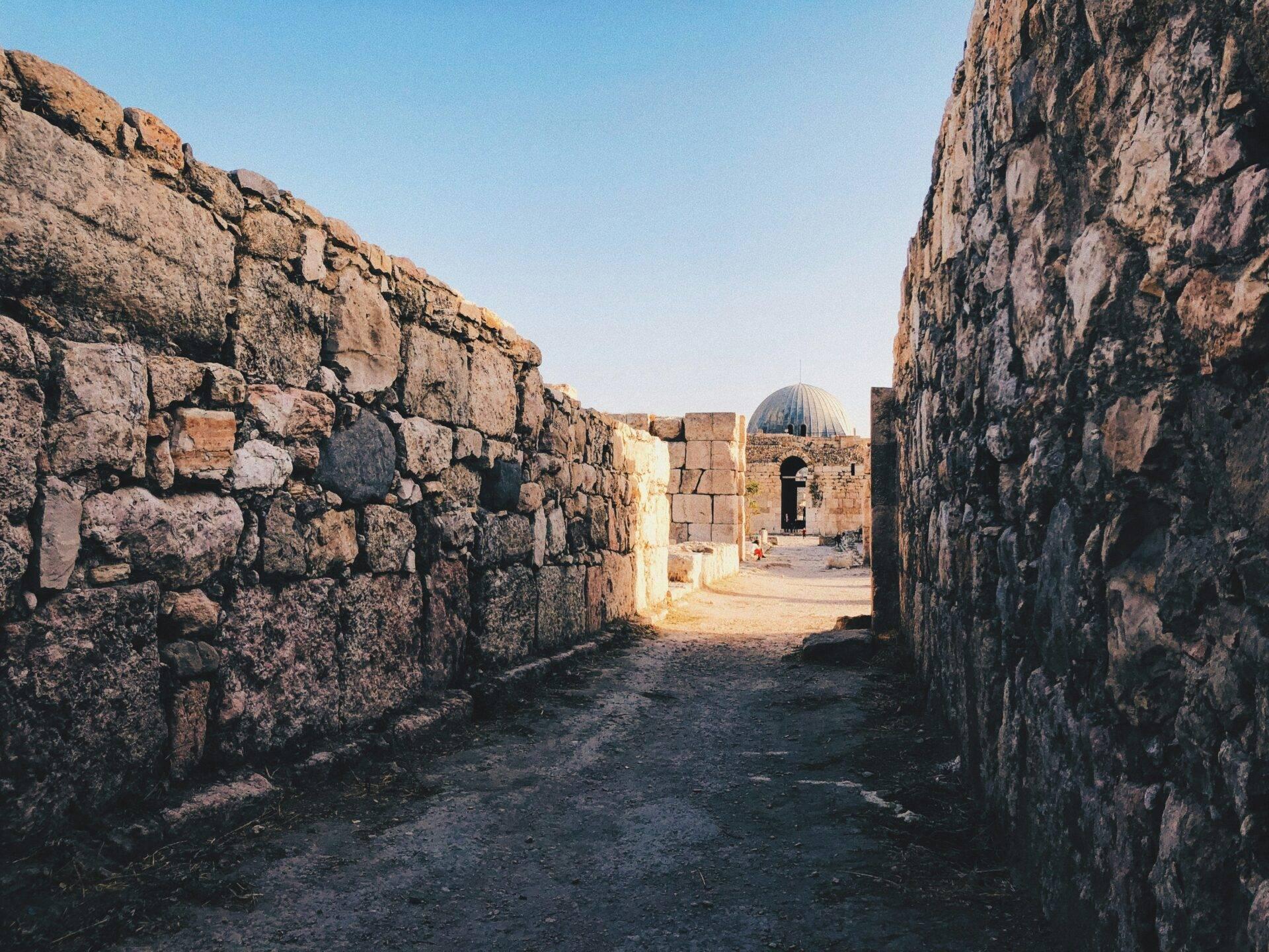Rovine in pietra di una fortezza storica con cupola architettonica al centro, sotto un cielo sereno