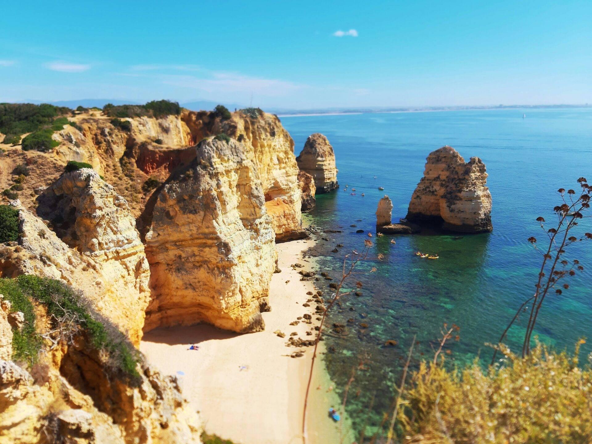 Scogliere dorate e spettacolari formazioni rocciose che si affacciano su una spiaggia di sabbia bianca e un mare turchese cristallino