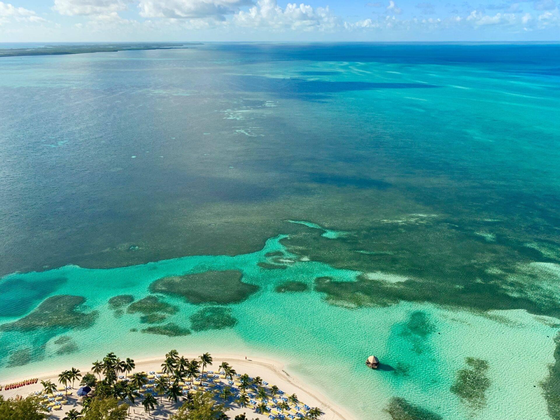 Vista aérea de una playa paradisíaca con aguas turquesas bordeada de palmeras e islotes boscosos