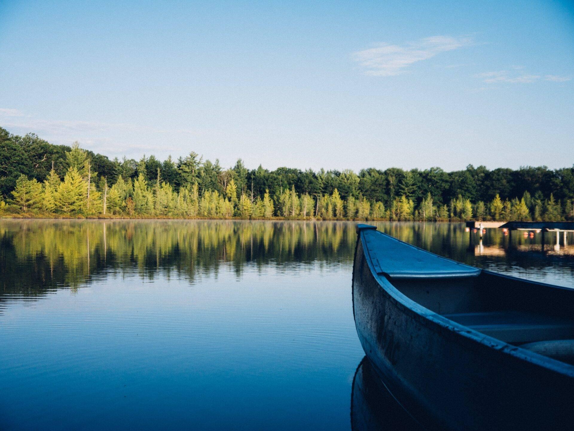 Ein blaues Boot, vertäut an einem ruhigen See, umgeben von Nadelwäldern unter klarem Himmel