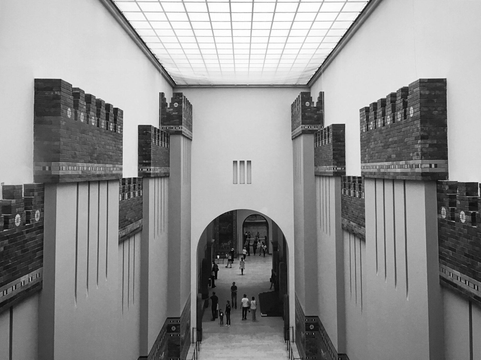 Architectural reconstruction of an ancient city gate with massive towers and visitors passing through a central arch