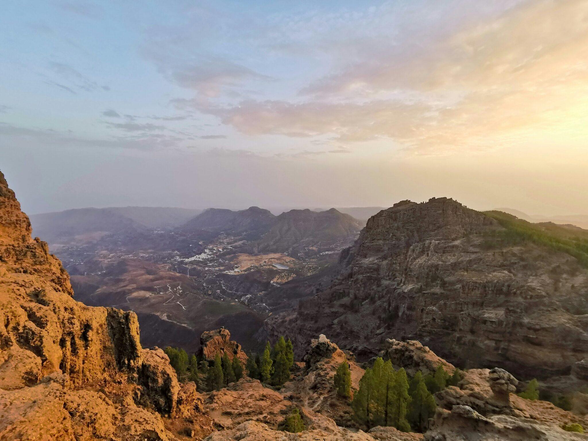 Vue panoramique d’une vallée montagne aux falaises rocheuses au coucher de soleil avec villages dispersés
