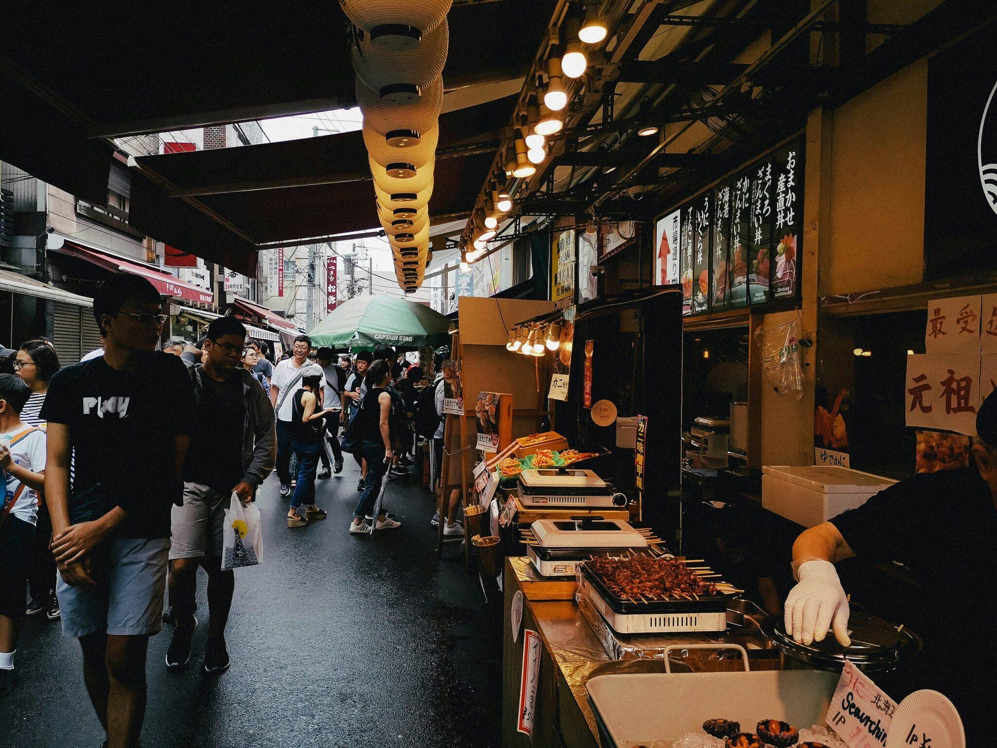 Une rue commerçante animée la nuit avec des vendeurs de street food grillée sous des lanternes jaunes traditionnelles