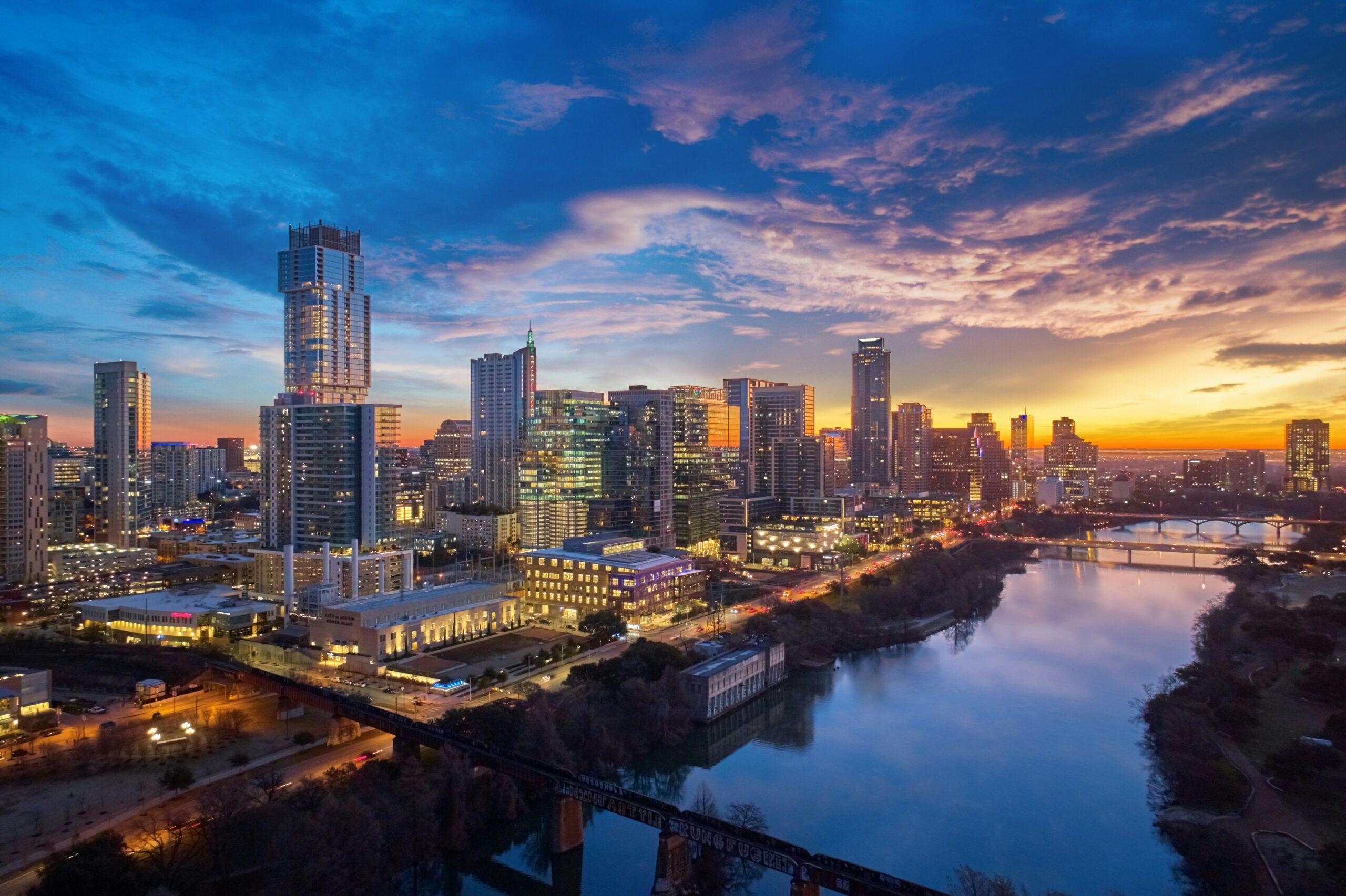 Skyline d’une grande ville américaine illuminée au coucher de soleil avec gratte-ciel et rivière reflétant les lumières