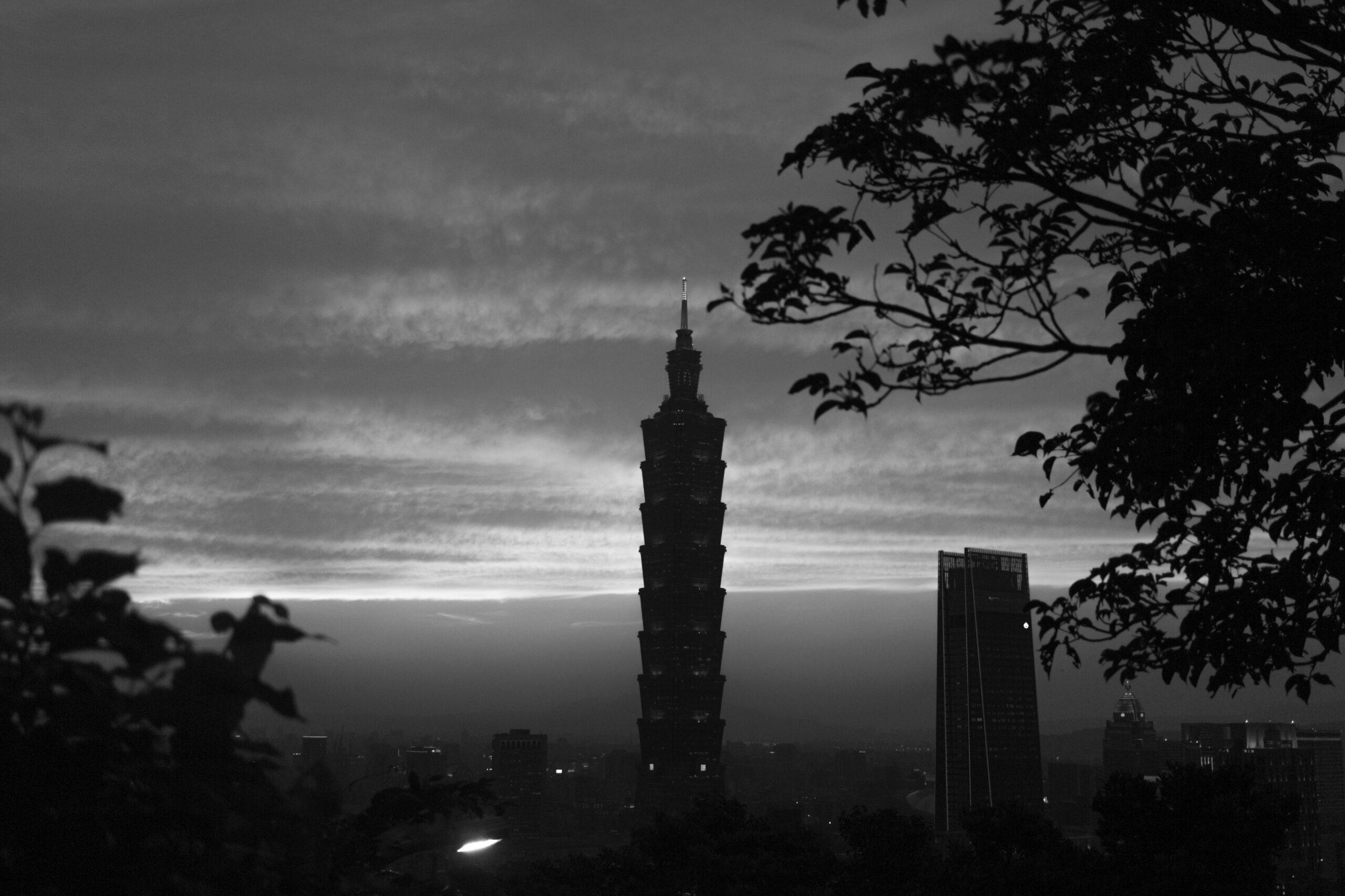 Vue panoramique au crépuscule d’une tour élancée dominante avec buildings modernes encadrée par des feuillages