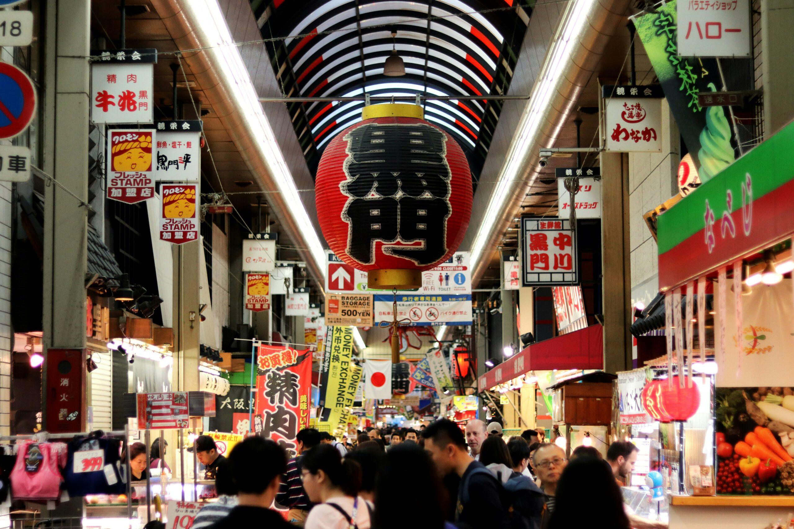 Rue commerçante couverte animée au Japon avec grande lanterne rouge traditionnelle et façades colorées de restaurants
