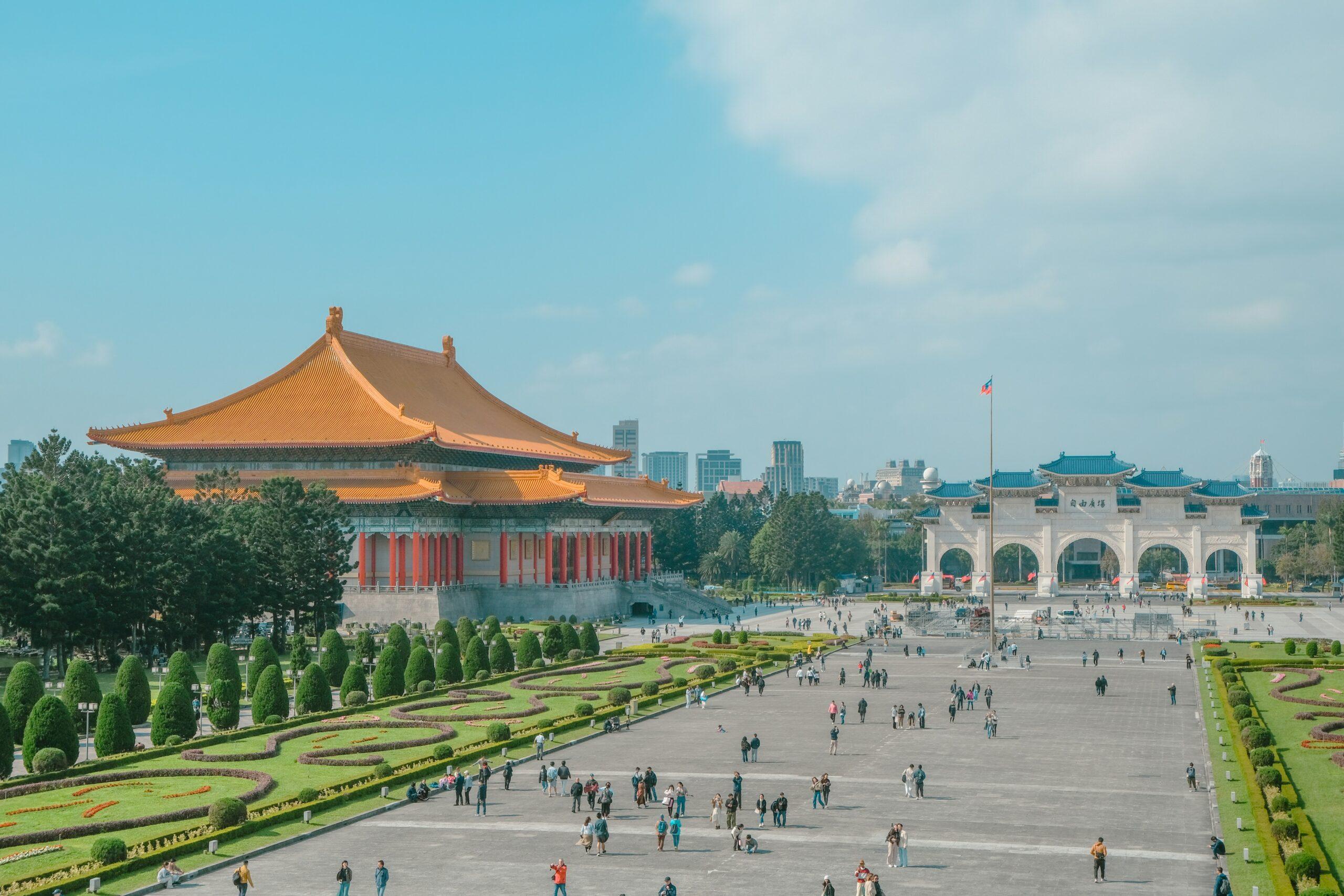 Une vaste place avec temple asiatique aux toits dorés, gate cérémoniel blanc et jardins paysagers, foule de visiteurs