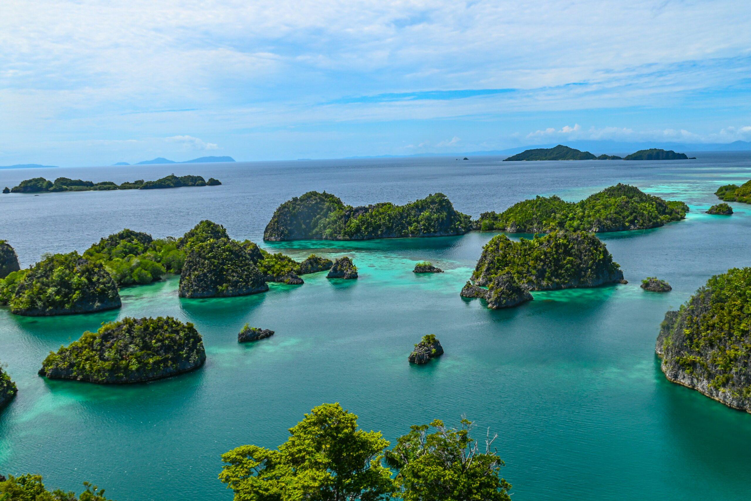 Vue aérienne d’un archipel tropical avec îles calcaires couvertes de végétation entourant une eau turquoise cristalline