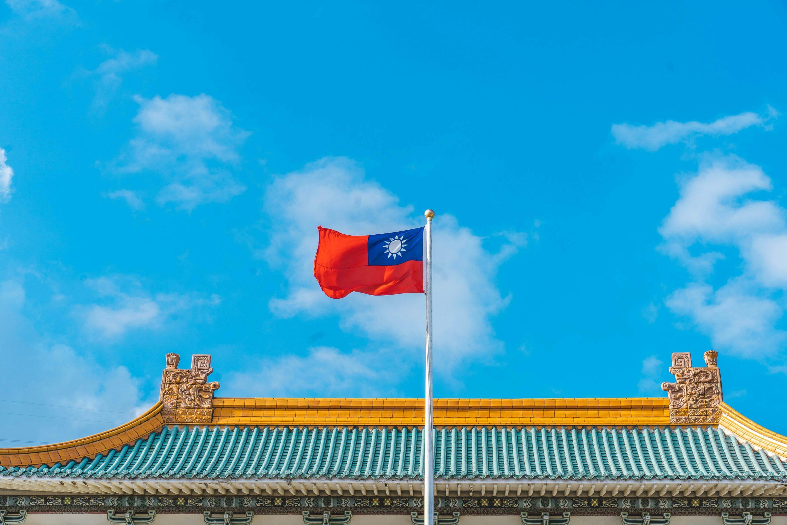 Le drapeau de Taïwan flotte devant un temple traditionnel aux toits dorés et turquoise sous un ciel bleu