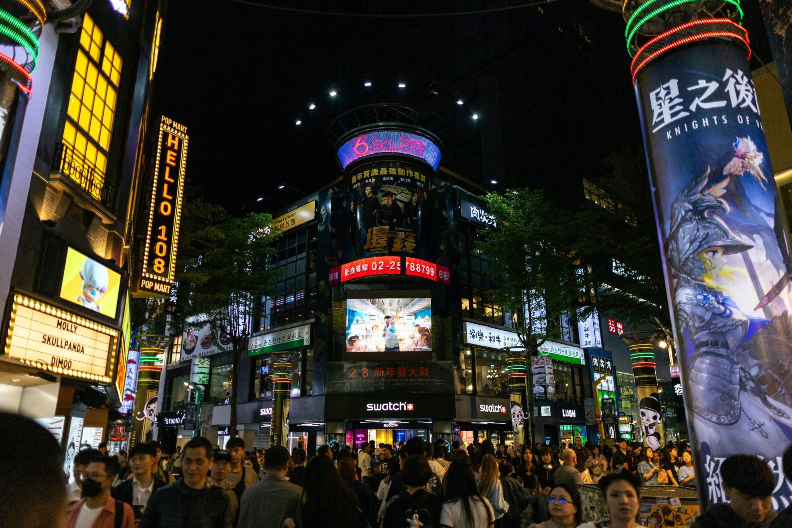 Une rue commerçante animée de nuit avec enseignes lumineuses, écrans géants et foules de piétons dans un quartier urbain asiatique