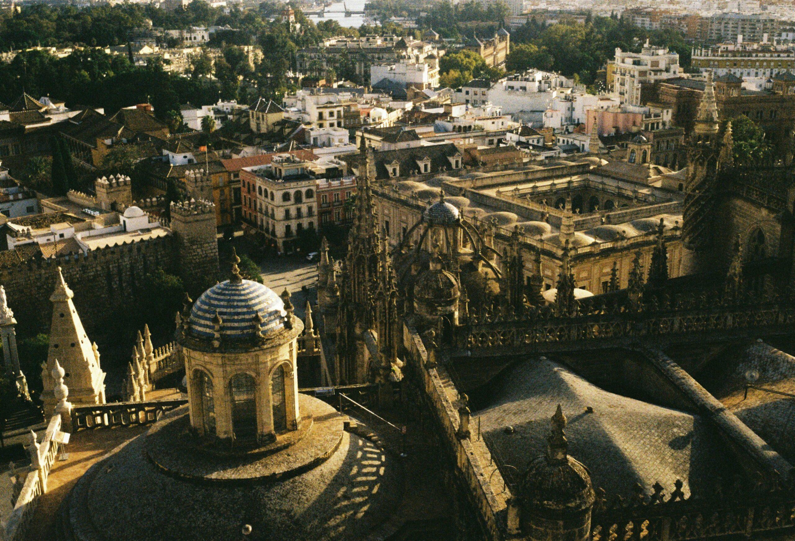Vista aerea della Cattedrale di Siviglia con i tetti dorati, circondata da edifici storici e giardini andalusi