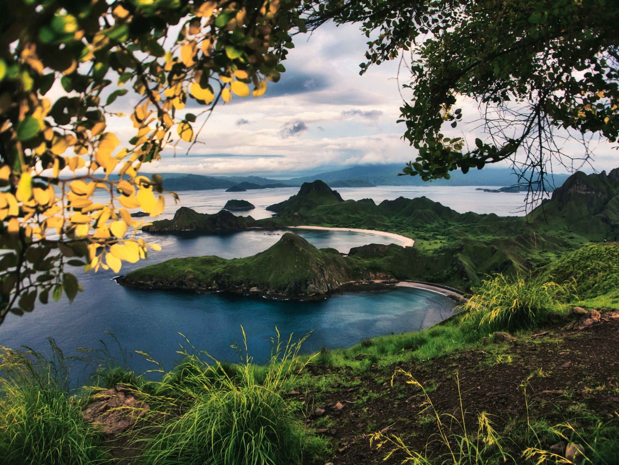 Vue panoramique d’îles verdoyantes avec plages de sable blanc, lagon turquoise et montagnes boisées en arrière-plan