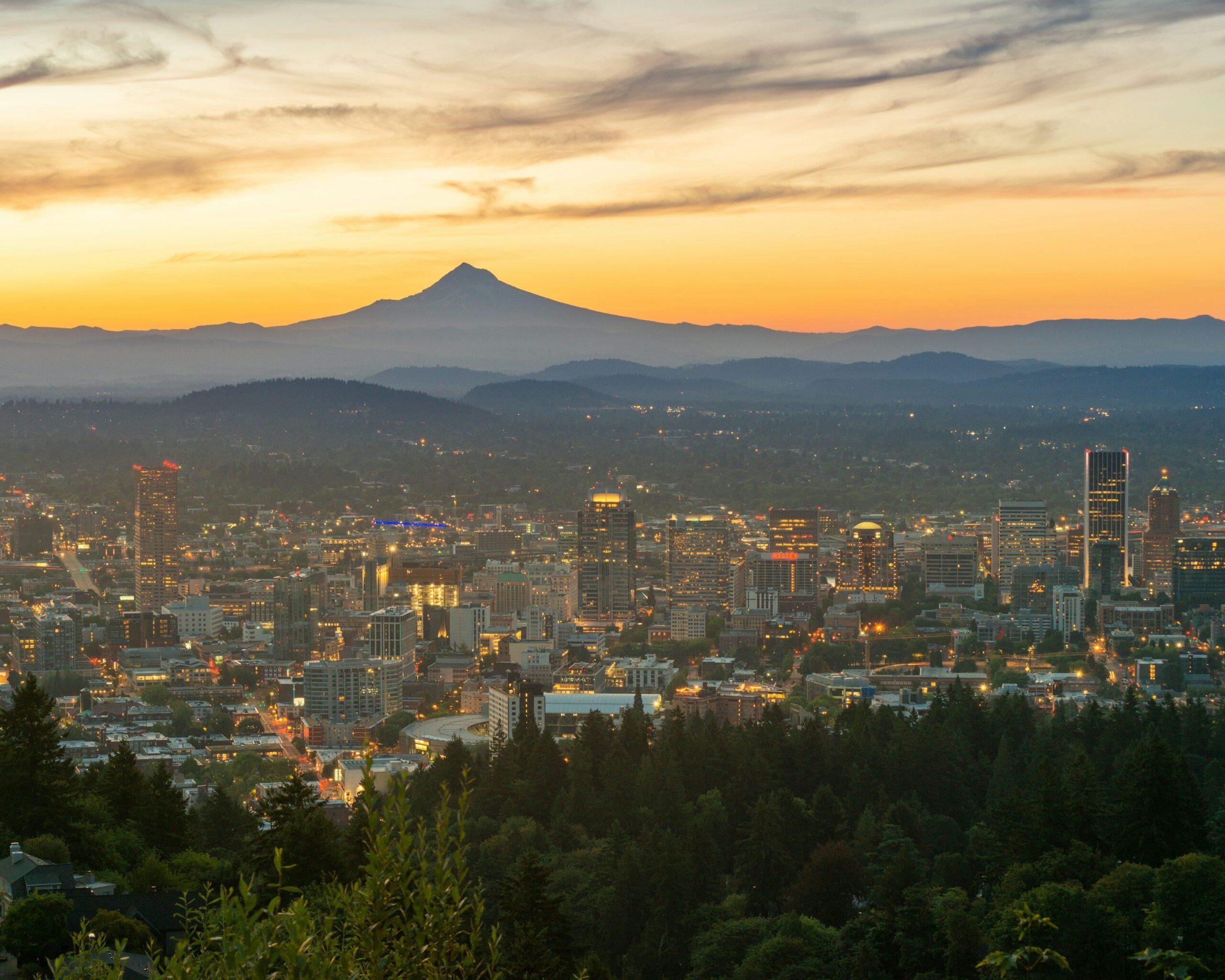 Une ville illuminée au crépuscule avec une montagne majestueuse en arrière-plan et forêts en premier plan