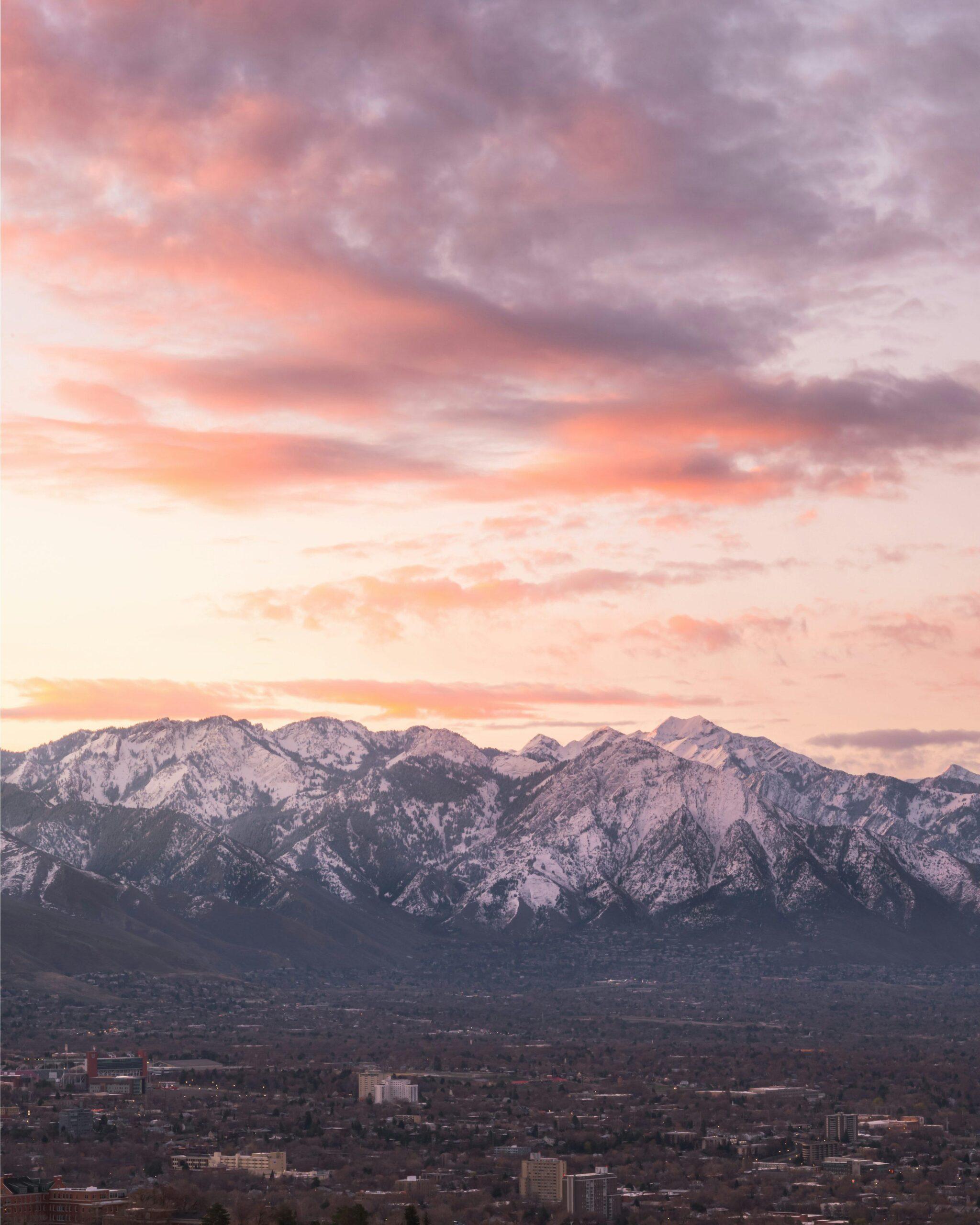 Vue panoramique d’une ville de montagne au coucher de soleil avec chaîne montagneuse enneigée en arrière-plan
