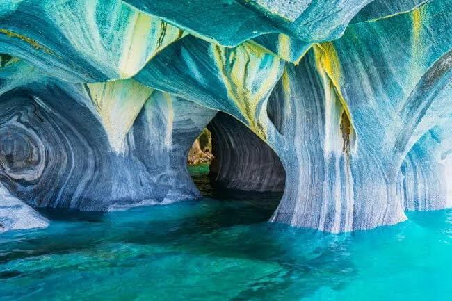 Ausgehöhlte Kalksteinhöhlen mit blau-weißen Wänden über türkisklarem Wasser