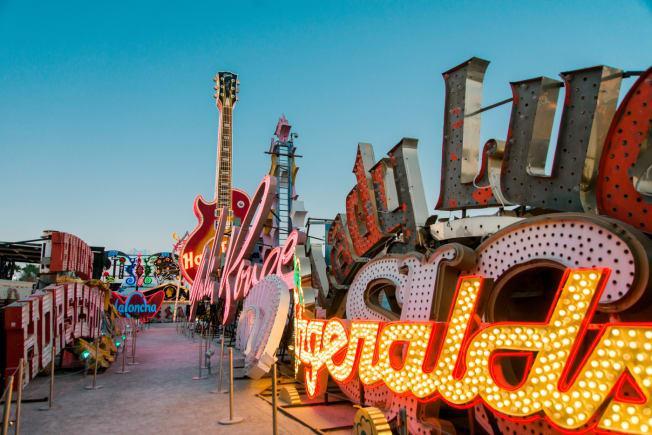 Un parc d’attractions avec des enseignes lumineuses colorées et des structures de jeux géantes sous un ciel bleu clair