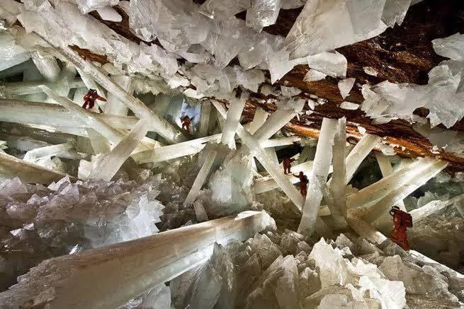Forscher laufen zwischen riesigen, lichtdurchlässigen Selenitkristallen in einer spektakulären unterirdischen Höhle