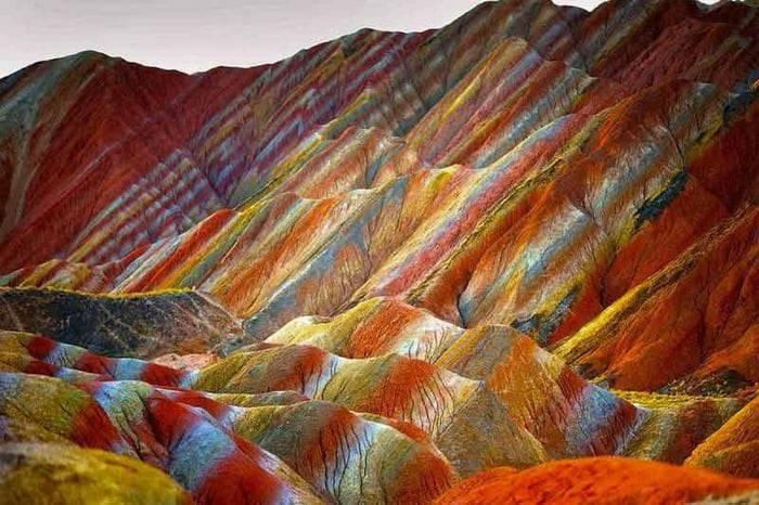 Bergzüge mit farbigen Schichten aus Rot, Orange, Gelb und Blau, die spektakuläre geometrische Muster bilden
