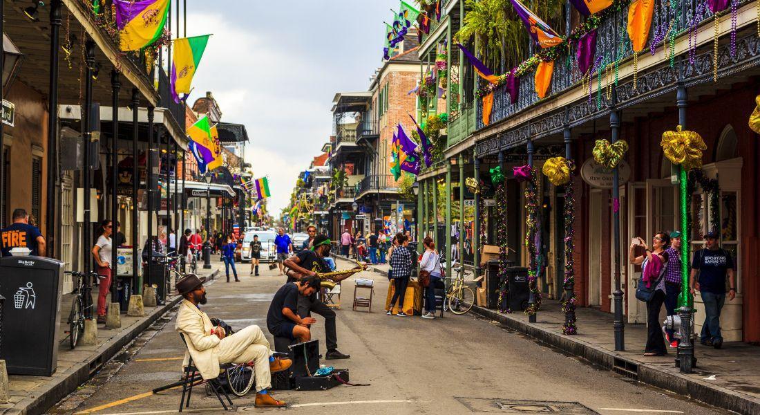 Une rue piétonne festive décorée de guirlandes colorées et de drapeaux, avec musiciens et passants flânant sous une ambiance de fête populaire