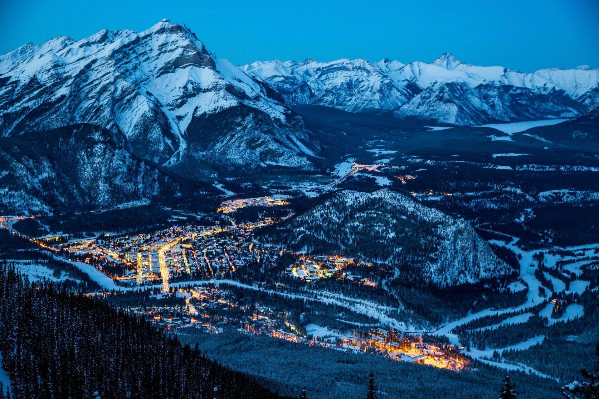 Vue nocturne d’une station de montagne enneigée illuminée dans une vallée alpine hivernale