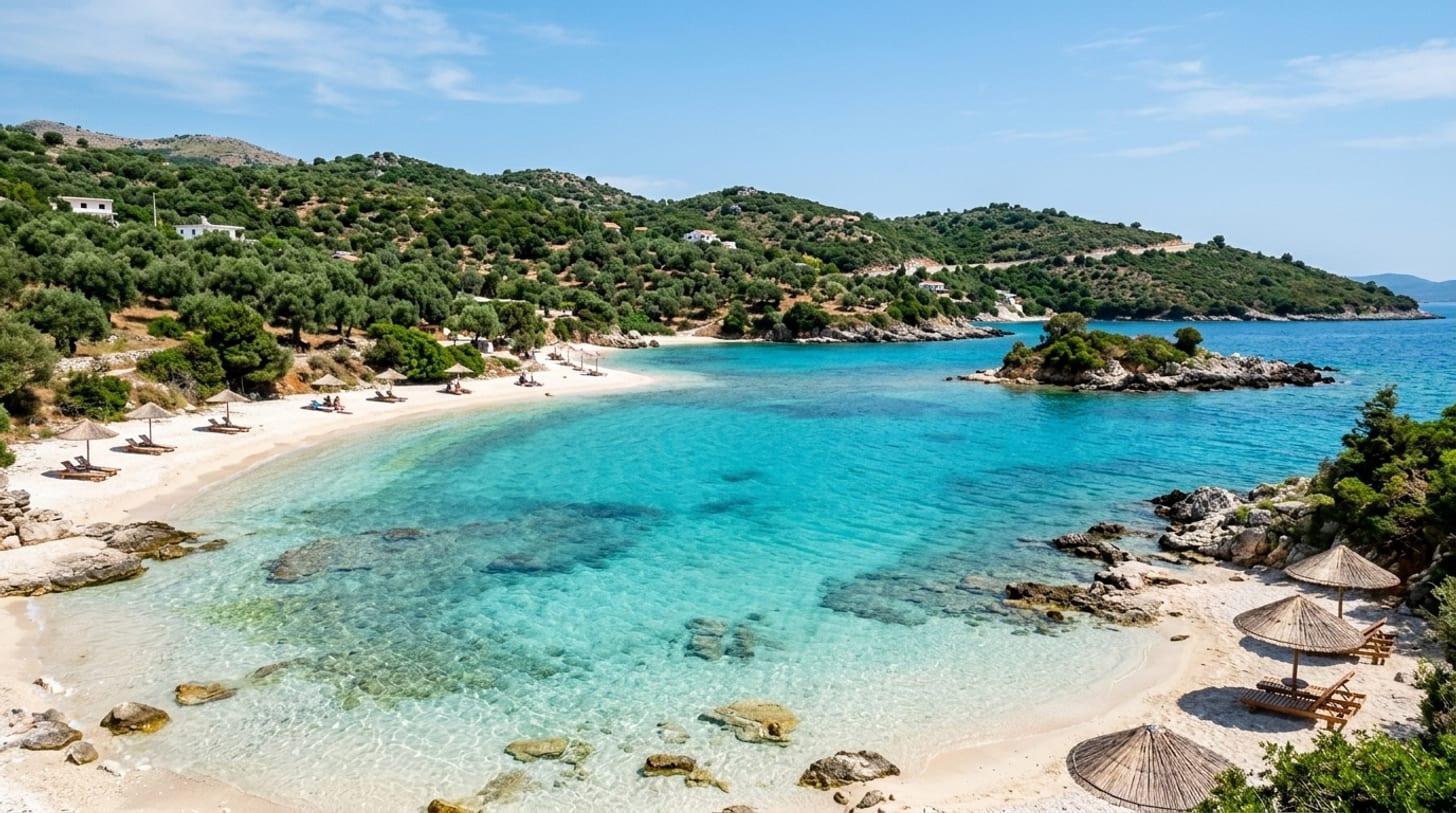 Crique de la Riviera albanaise près de Ksamil, eau turquoise translucide, sable blanc et collines d’oliviers