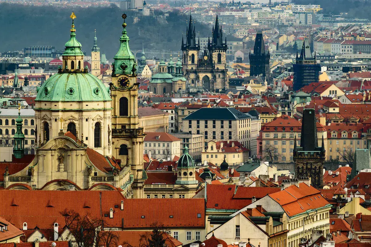 Vue panoramique d’une ville européenne avec églises aux dômes verts et tours gothiques noires dominant l’architecture historique