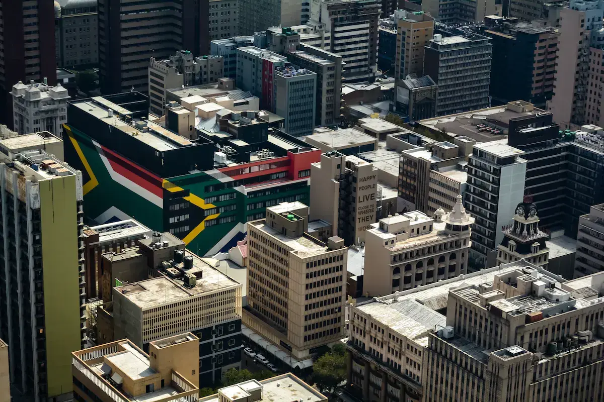 Vue aérienne d’un quartier urbain avec un bâtiment aux couleurs du drapeau sud-africain parmi les gratte-ciel