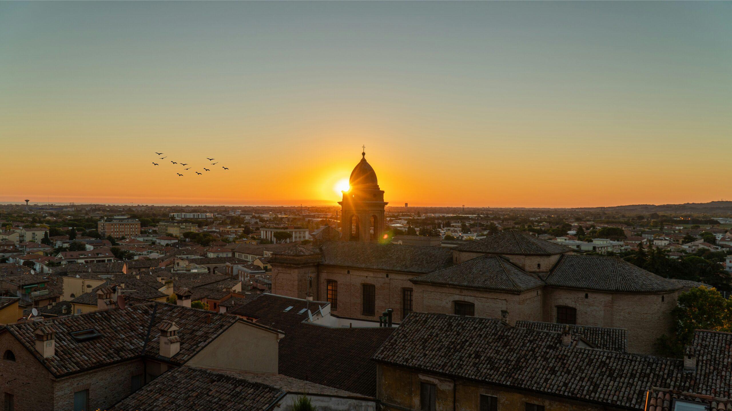 Coucher de soleil sur une cathédrale à dôme doré dominant les toits d’une ville italienne historique