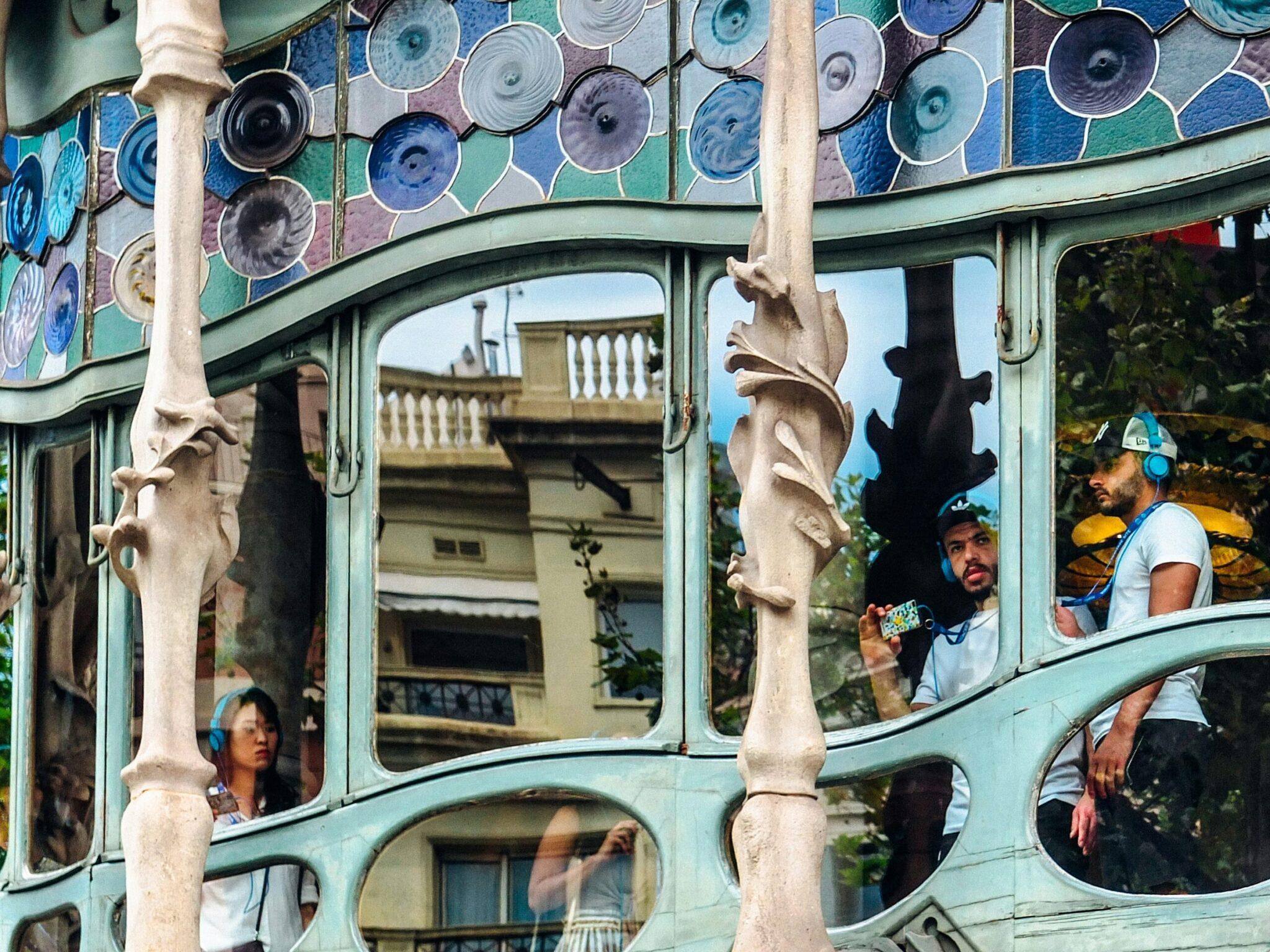 Façade colorée avec assiettes décoratives et personnes aux fenêtres d’un bâtiment historique de Barcelone