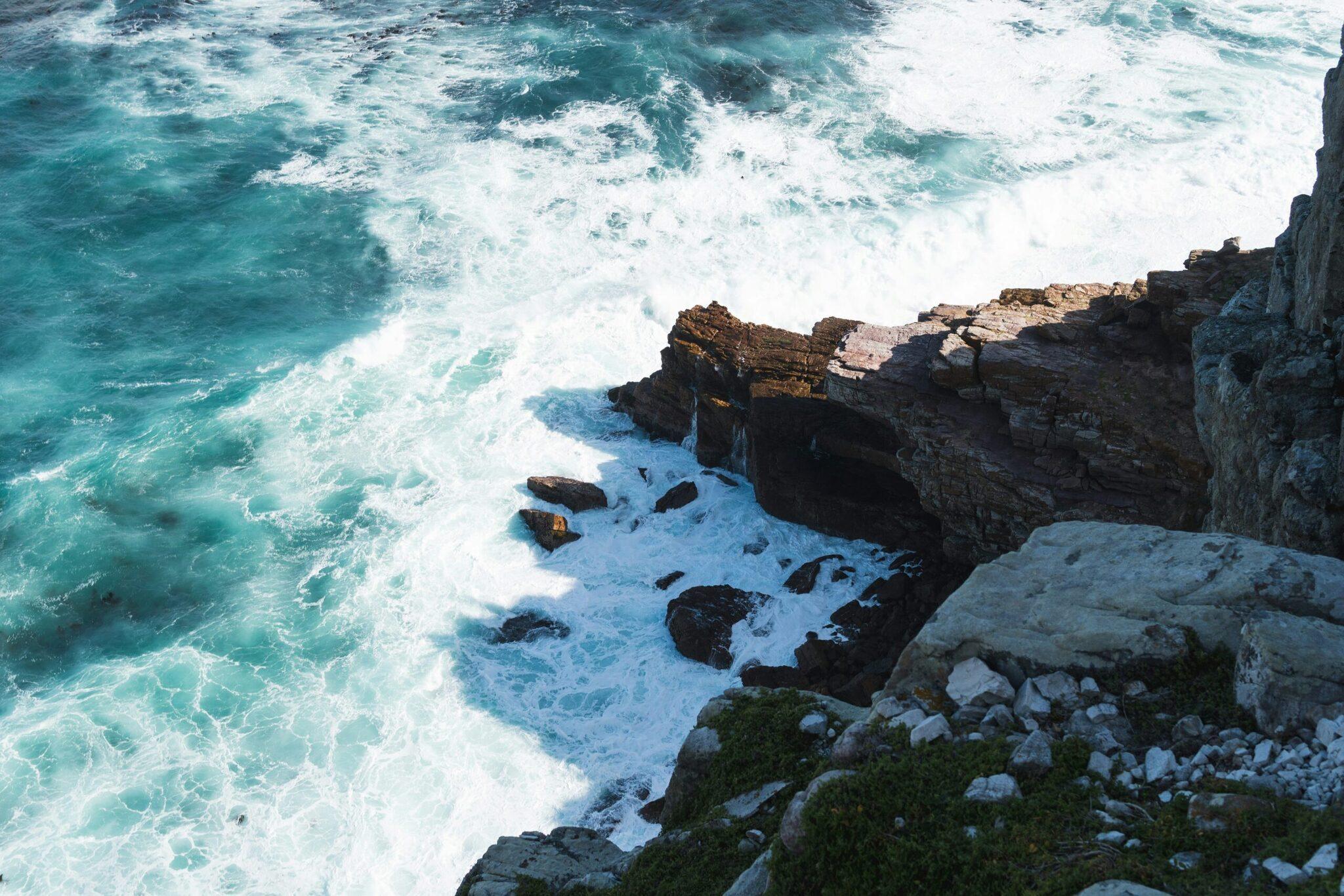 Vagues turquoise déferlant contre des falaises rocheuses escarpées surplombant l’océan