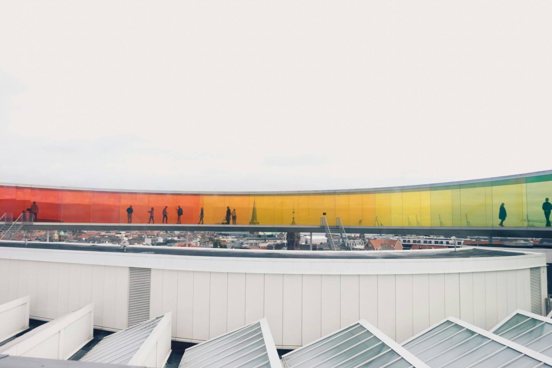 Une terrasse panoramique offre une vue sur une ville avec un bâtiment moderne aux façades colorées arc-en-ciel
