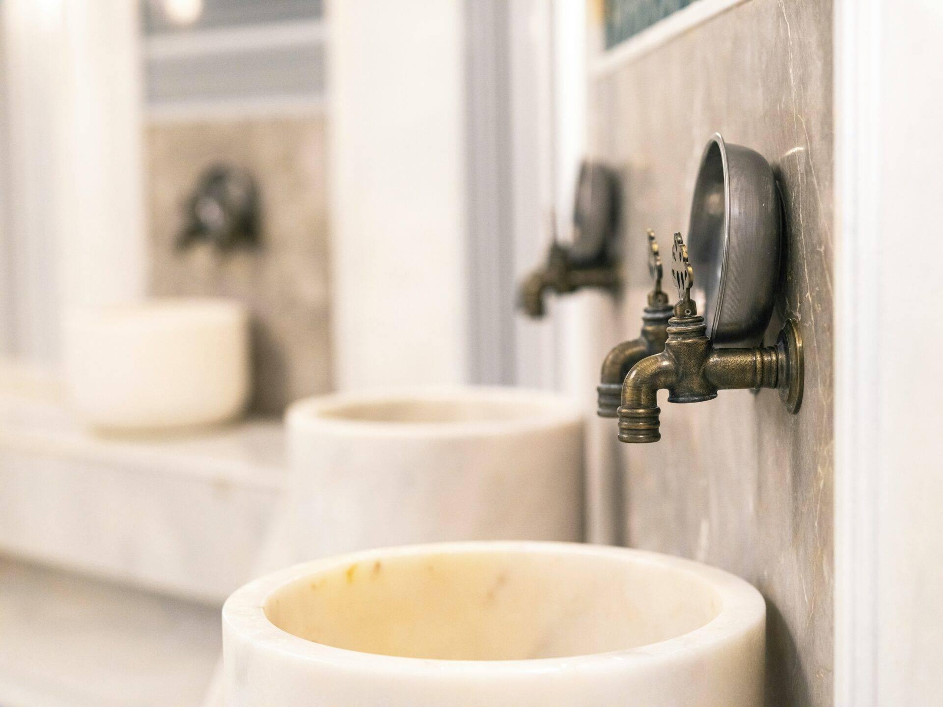 Détail d’un robinet en laiton ancien dans une salle d’eau traditionnelle avec carrelage beige