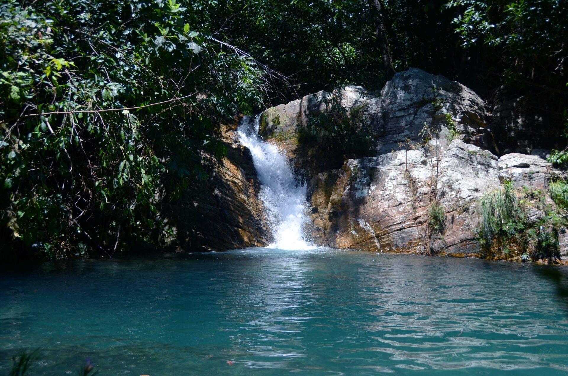 Une cascade cristalline s’écoule dans un bassin turquoise encadré de falaises rocheuses et de végétation tropicale luxuriante