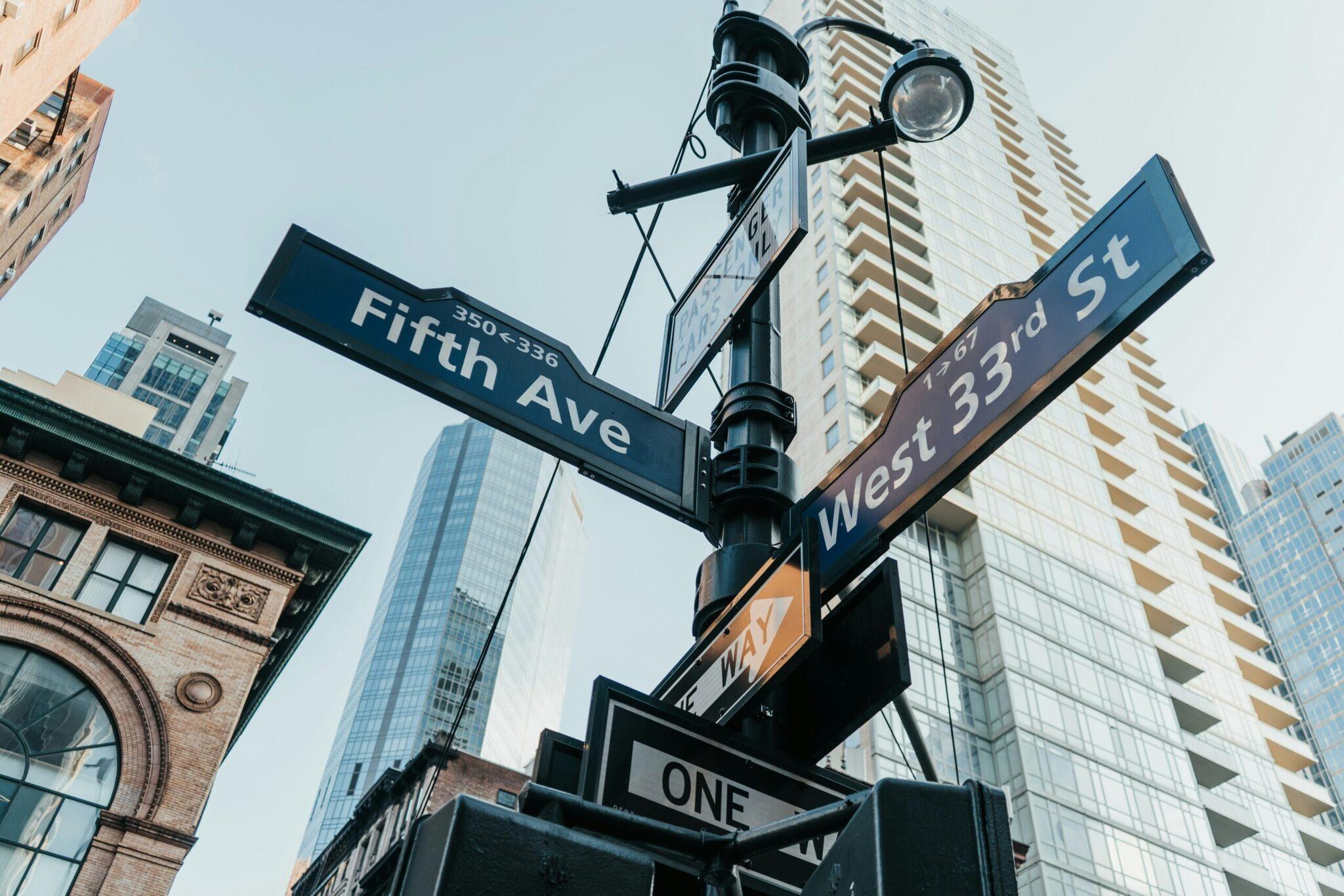 Carrefour urbain new-yorkais avec panneaux de rues Fifth Avenue et West 33rd Street, immeubles modernes et architecture historique