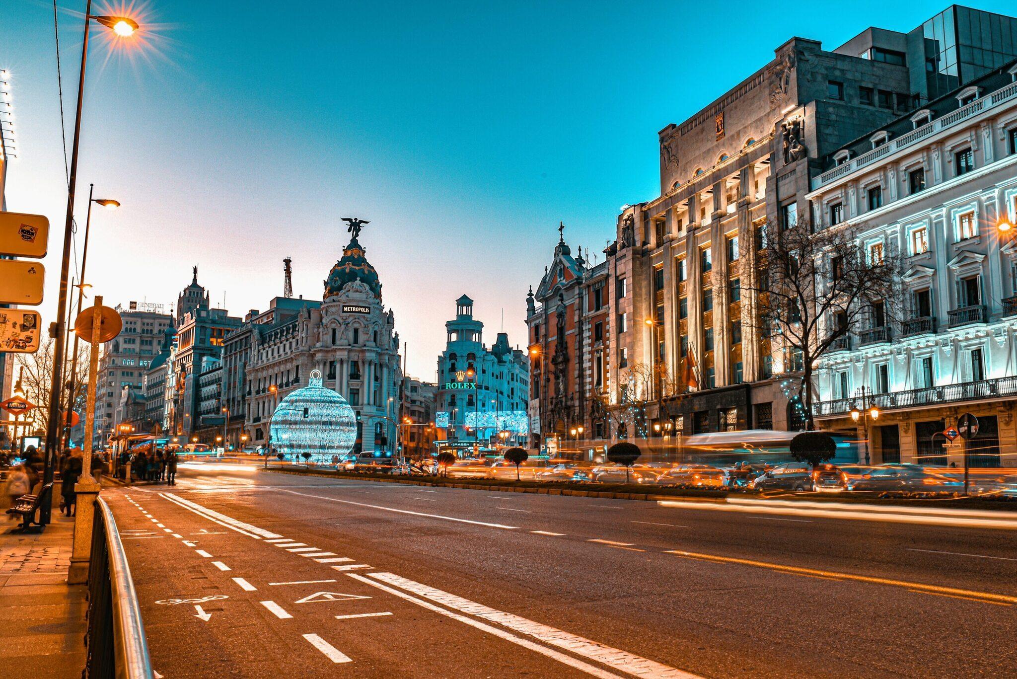 Une avenue urbaine illuminée au crépuscule avec immeubles historiques, monuments architecturaux et circulation routière