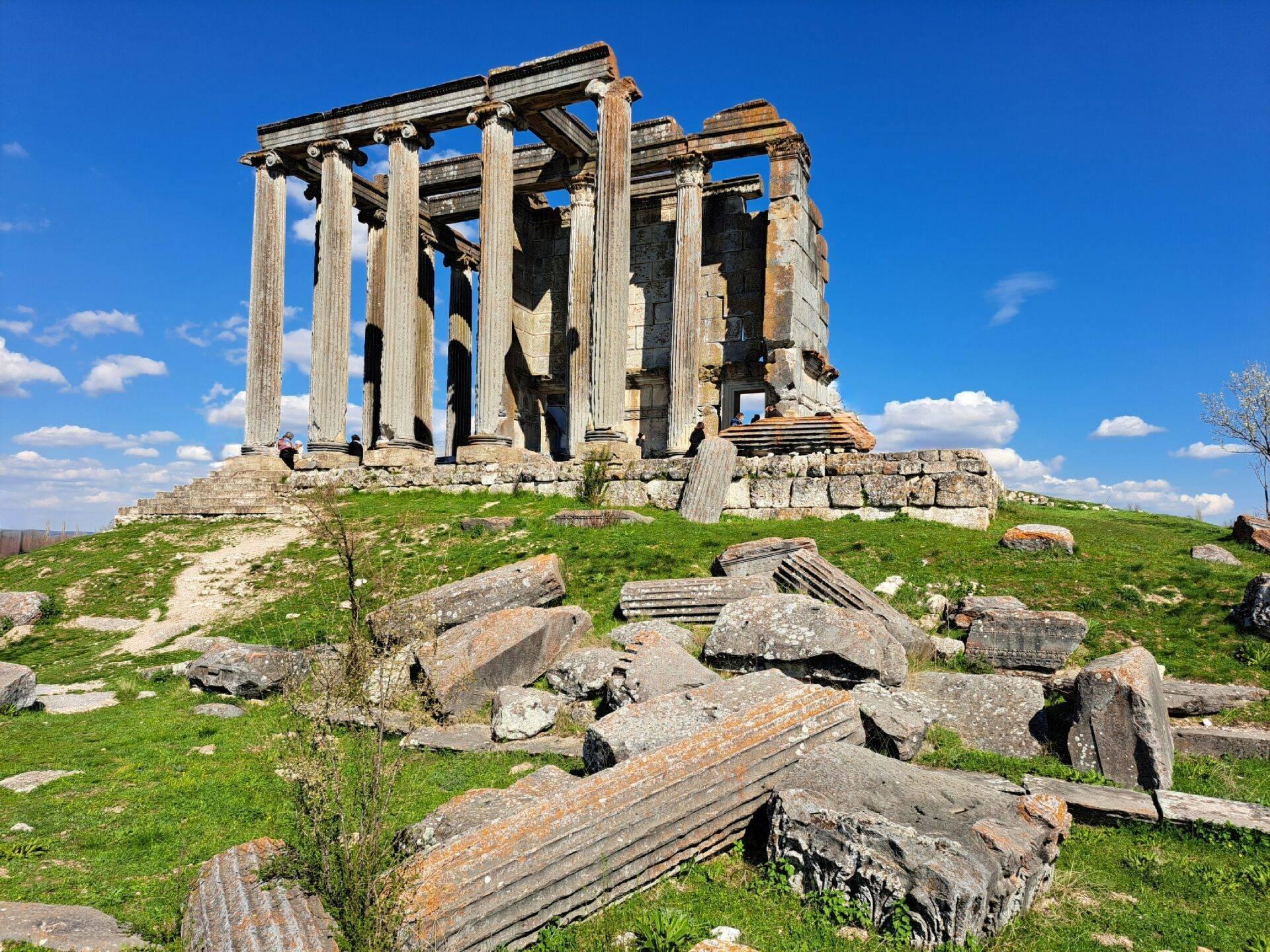 Ruines d’un temple antique avec colonnes doriques sur une colline verdoyante sous un ciel bleu dégagé