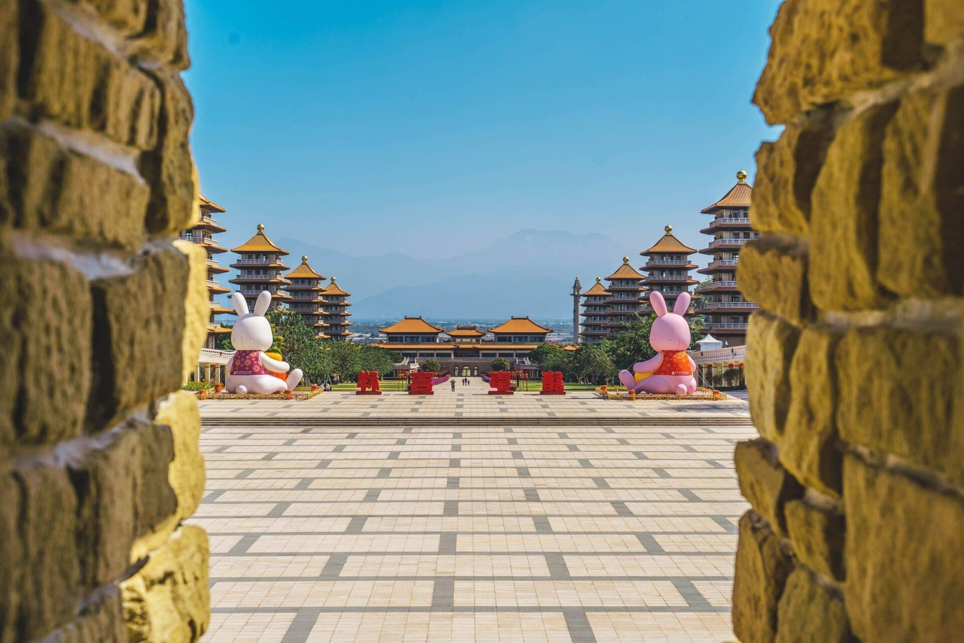 Vue sur une cour de temple asiatique avec pagodes dorées encadrée par des murs verts sculptés