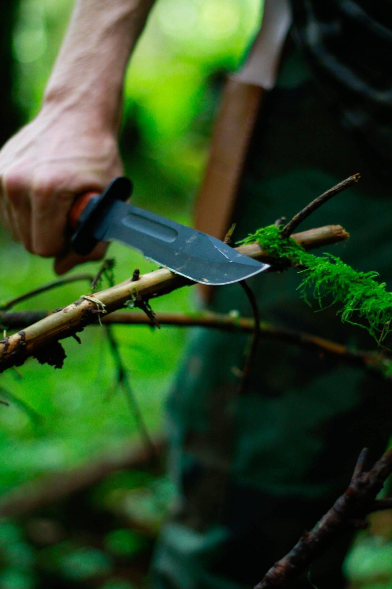 Randonneur en terrain sauvage consultant l’application SAS Survival Guide sur son smartphone pour des conseils de survie