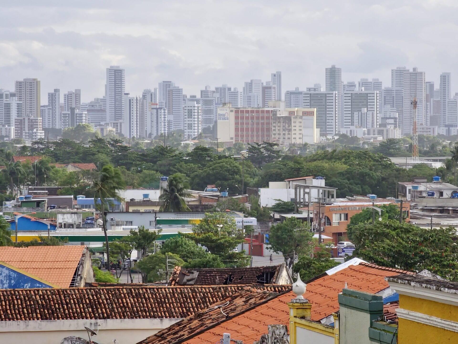 Vue sur les toits colorés d’un quartier résidentiel contrastant avec les gratte-ciel d’une métropole brésilienne en arrière-plan