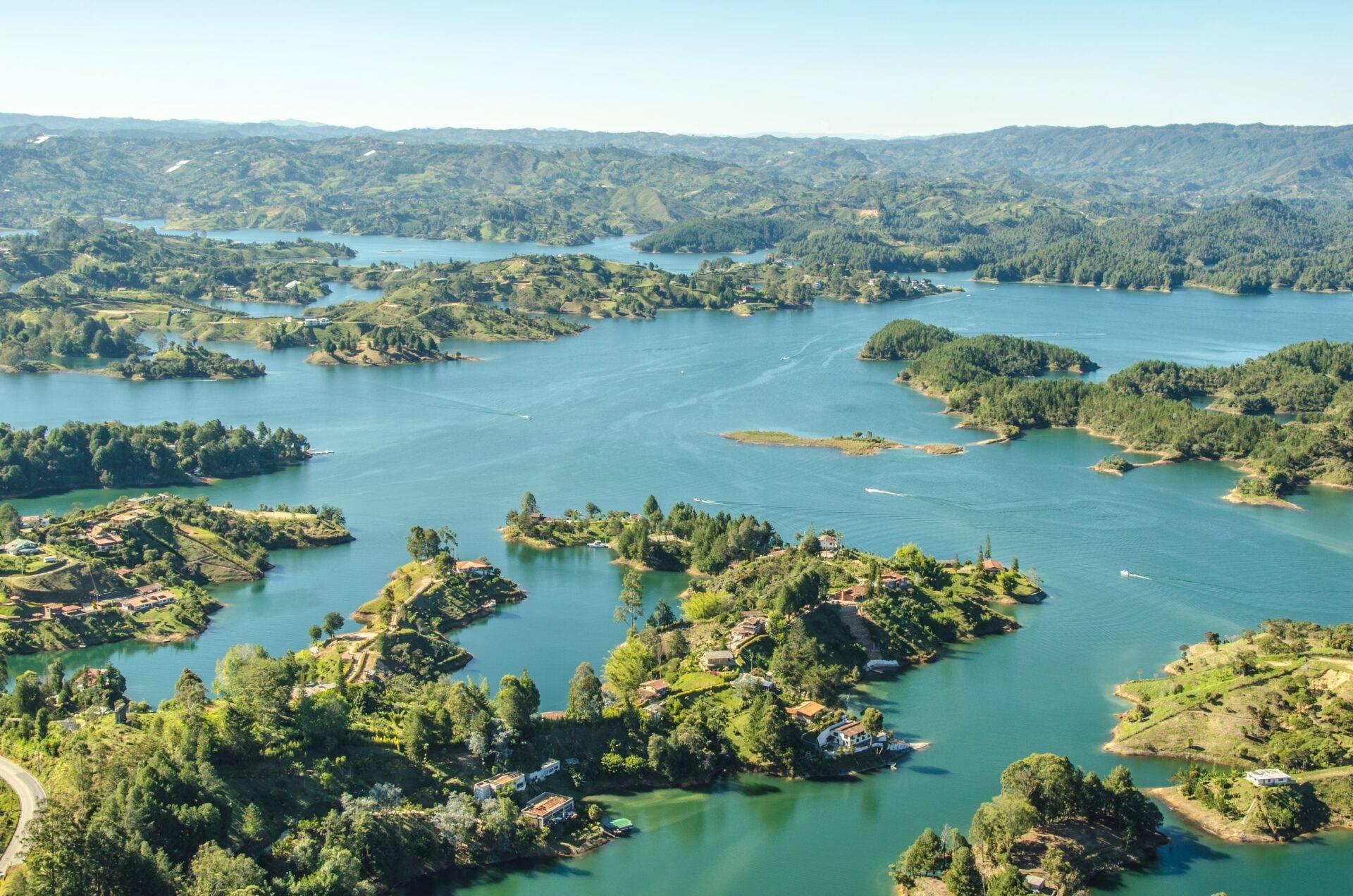 Vue aérienne d’un vaste système lacustre montagneux avec îles boisées et maisons dispersées en région tropicale