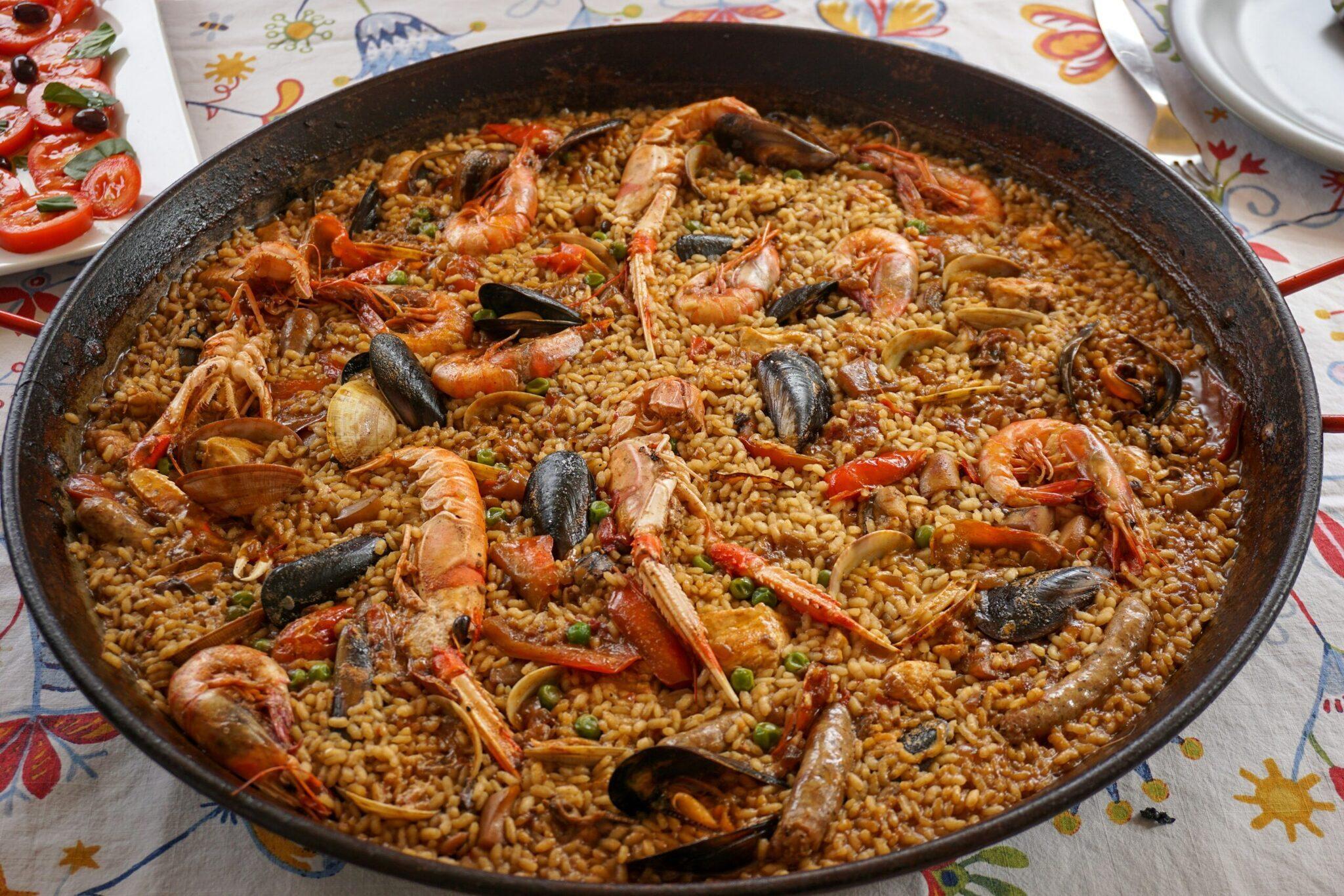 Une paella aux fruits de mer avec crevettes, moules et pois dans un plat traditionnel en fer