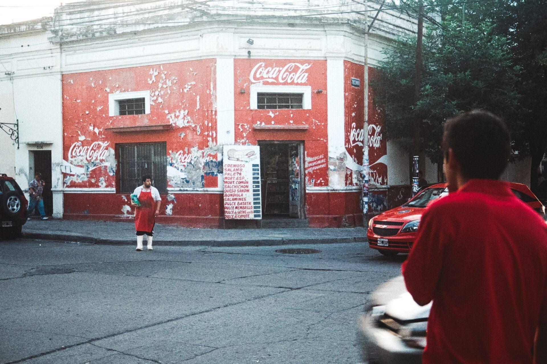 Une rue de quartier populaire en Amérique latine avec un bâtiment aux murs rouges peints de logos publicitaires vintage